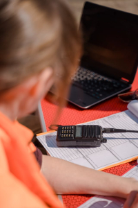 A two-way radio is kept over a book, on a table, beside a working personnel