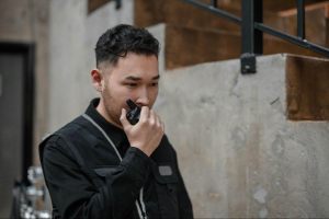 A construction worker on duty is using a two-way radio to connect with his co-worker