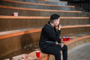 A man, sitting on a staircase, is conversing using a two-way radio