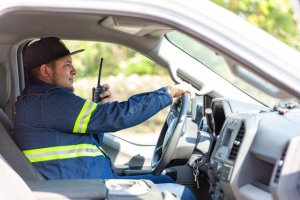 A person sitting in a car, is holding a two-way radio