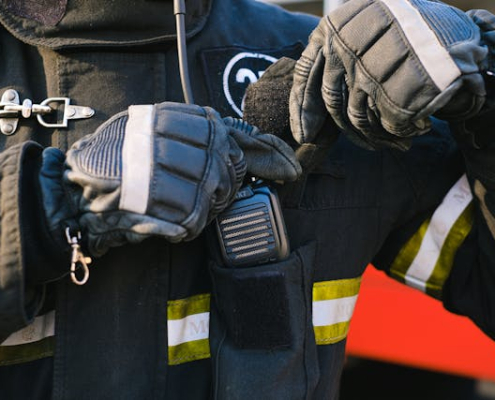 A man wearing a jacket and gloves, is seen putting a two-way radio in his pocket