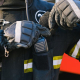 A man wearing a jacket and gloves, is seen putting a two-way radio in his pocket