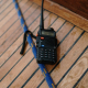 A two-way radio kept on a wooden-top table, nearby a rope