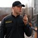 A guard using a two-way radio to handle the vehicle parking outside a sports venue
