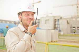 A man in a white helmet, using a two-way radio