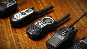 Two-way radios lined up on a wooden desk